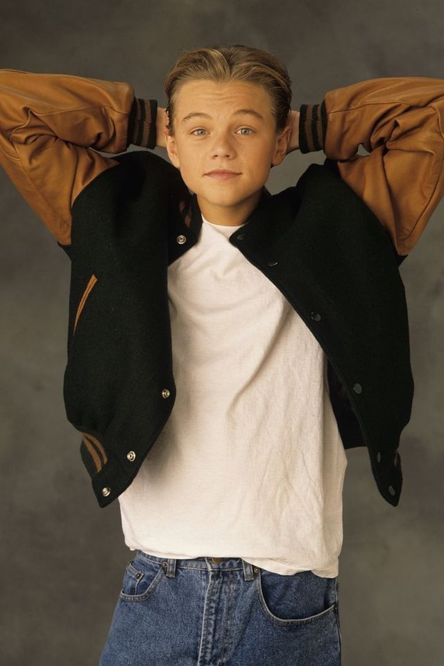 a young man with his hands on his head wearing a black jacket and white t - shirt