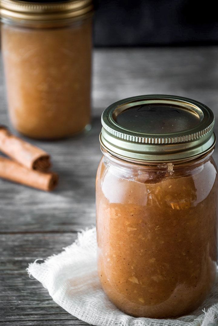 homemade cinnamon apple sauce in a glass jar with cinnamon sticks on the table next to it