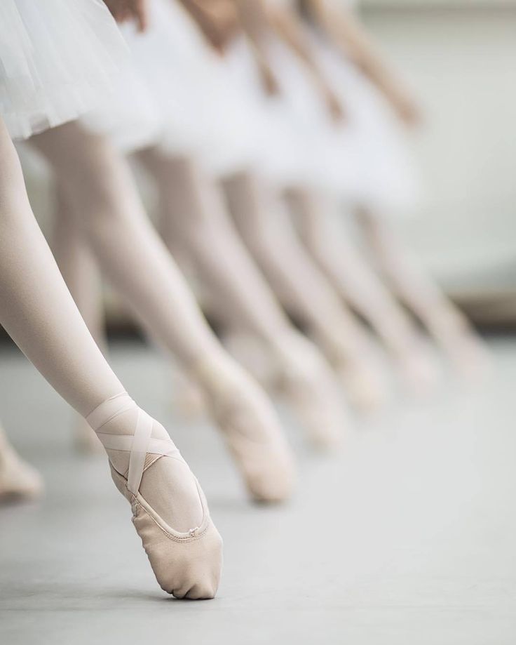 several ballet students are lined up with their feet in the air