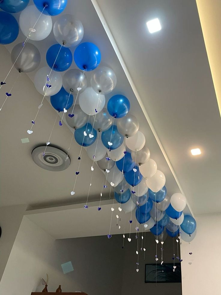 blue and white balloons are hanging from the ceiling