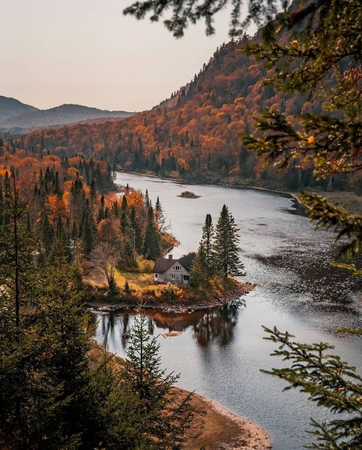 an island in the middle of a lake surrounded by trees with fall foliage on it