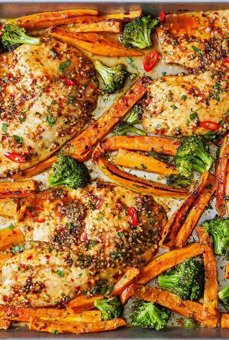 chicken, broccoli and sweet potato fries in a baking pan with seasoning sprinkled on top