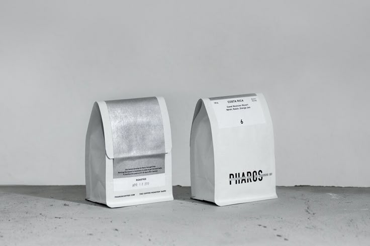 two white boxes sitting next to each other on top of a cement floor covered ground