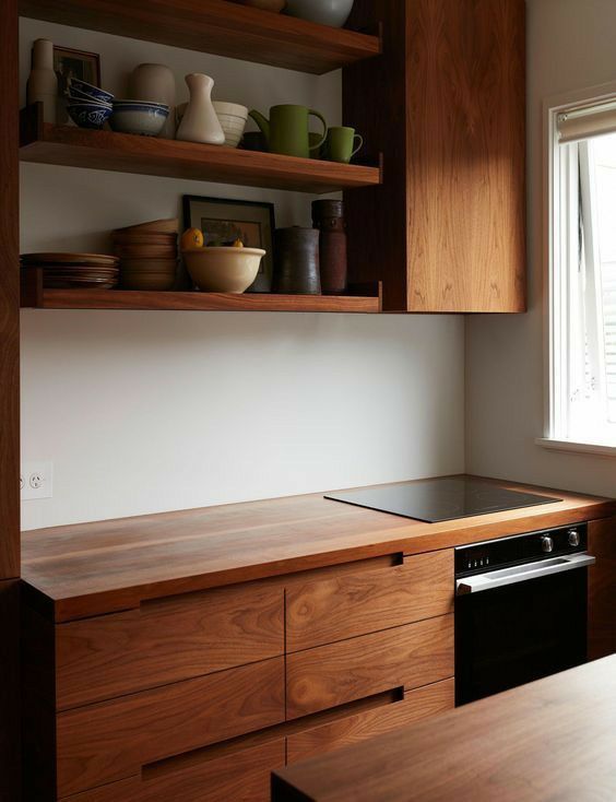 a kitchen with wooden cabinets and shelves filled with dishes on top of the counter tops