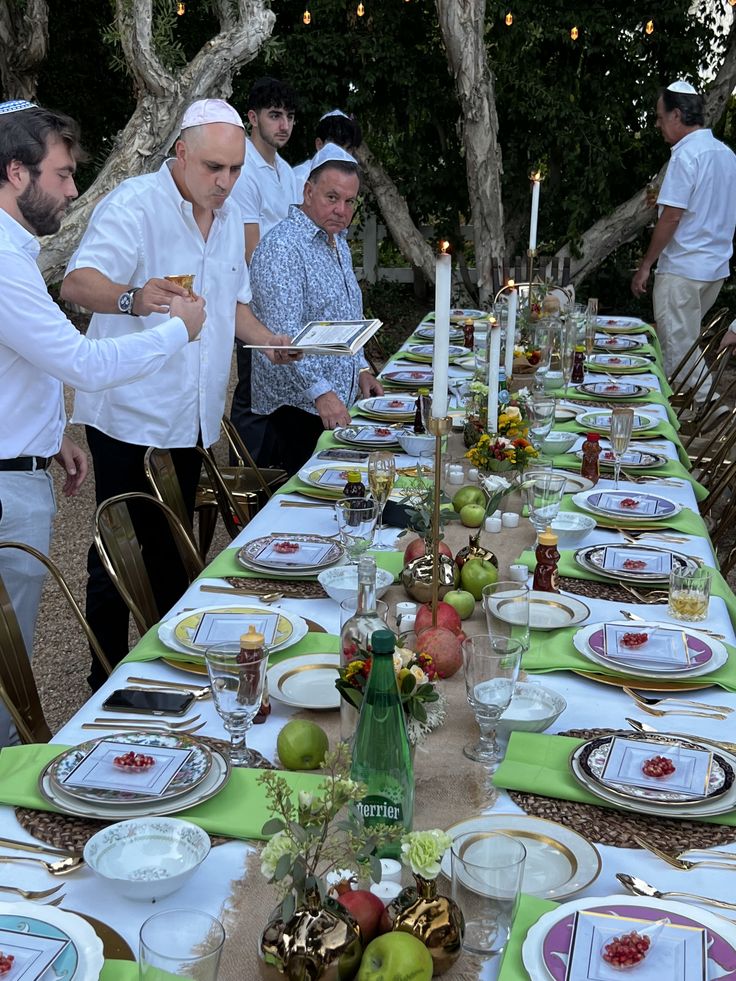 a group of men standing around a long table with plates and glasses on top of it