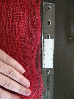 a person's hand on top of a piece of red fabric next to a ruler