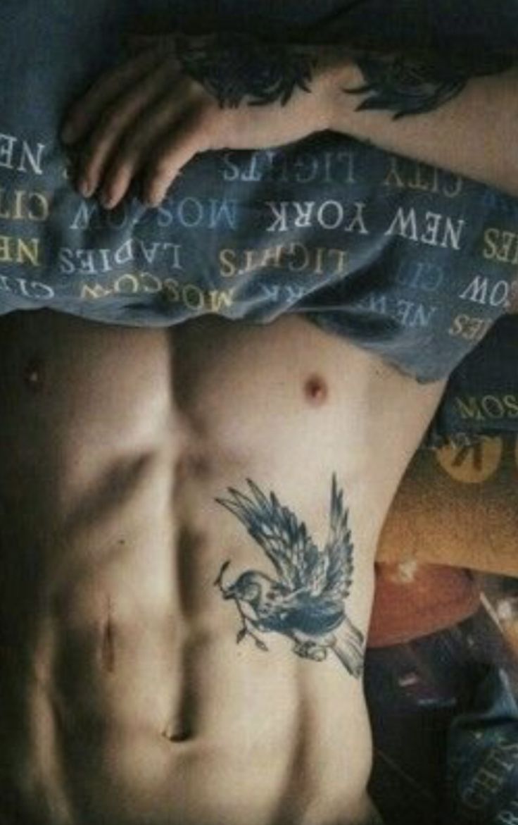 a man laying on top of a bed covered in lots of words and tattoos next to his stomach