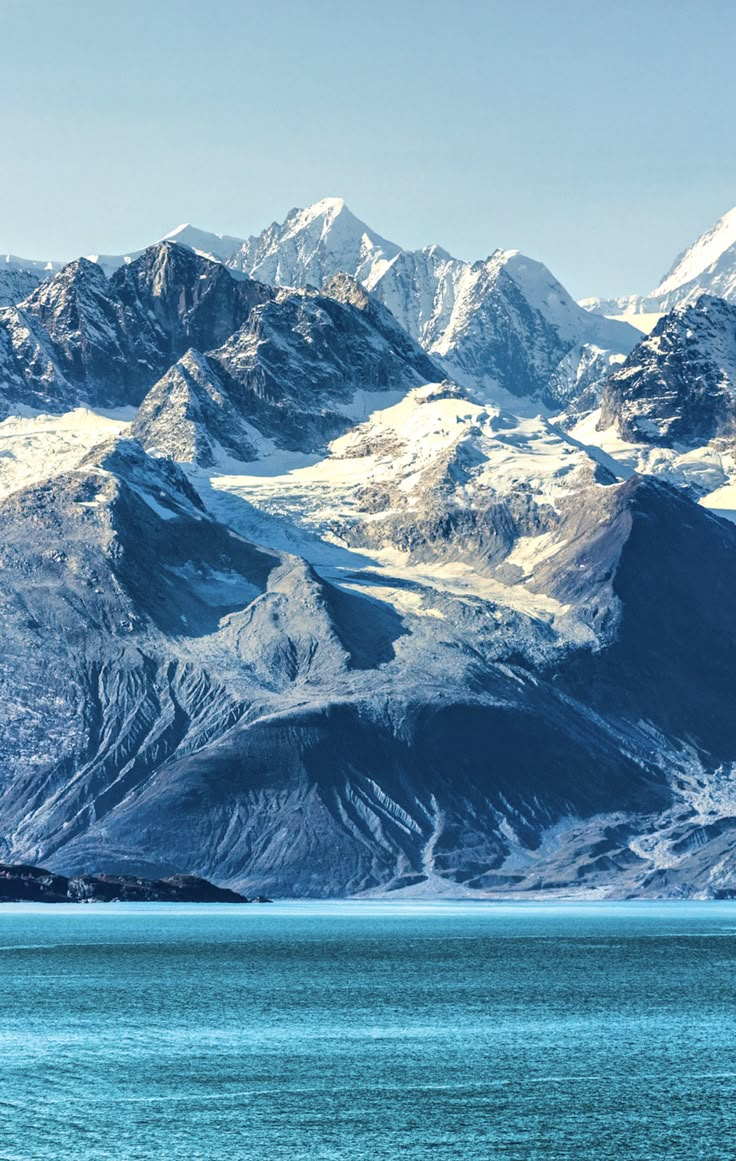 the mountains are covered in snow and blue water