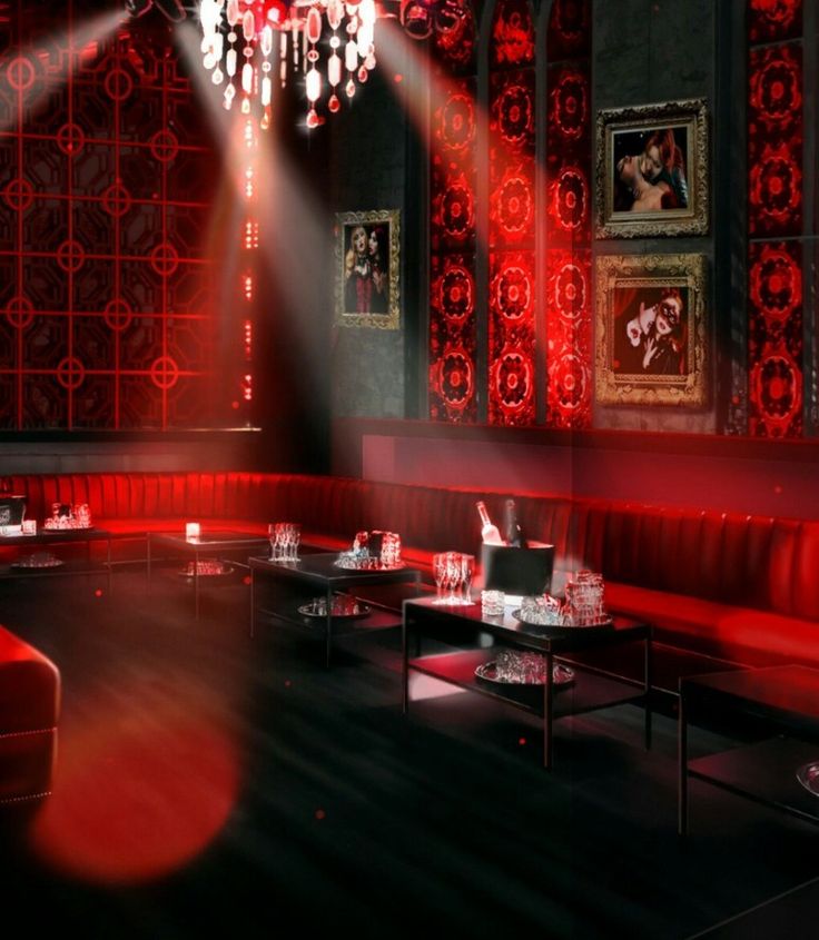 a dimly lit restaurant with red lighting and chandeliers on the walls, tables and booths