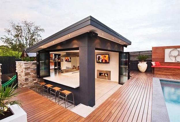 an outdoor living area with wooden decking and patio furniture next to a swimming pool