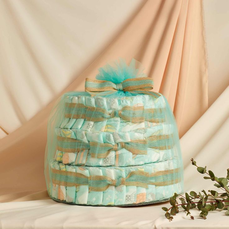 a stack of baby blankets sitting on top of a table next to a potted plant