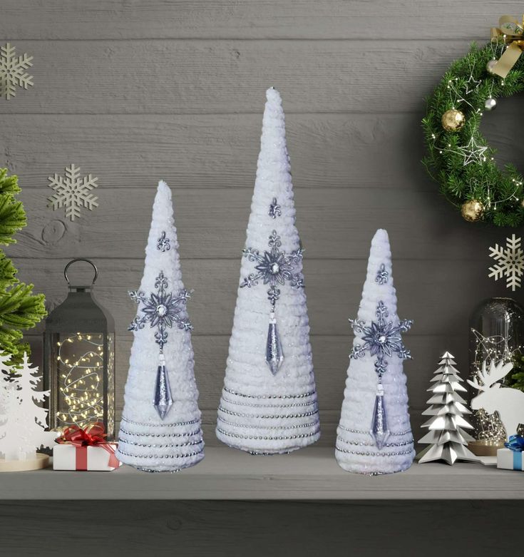 three white christmas trees sitting on top of a mantle