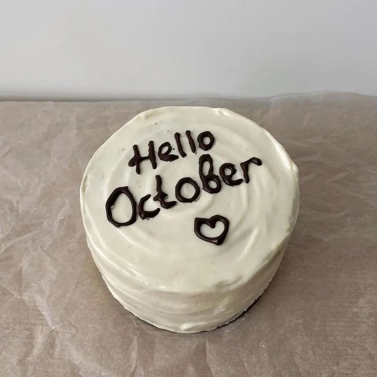 a cake with writing on it sitting on top of a piece of wax paper that says hello october