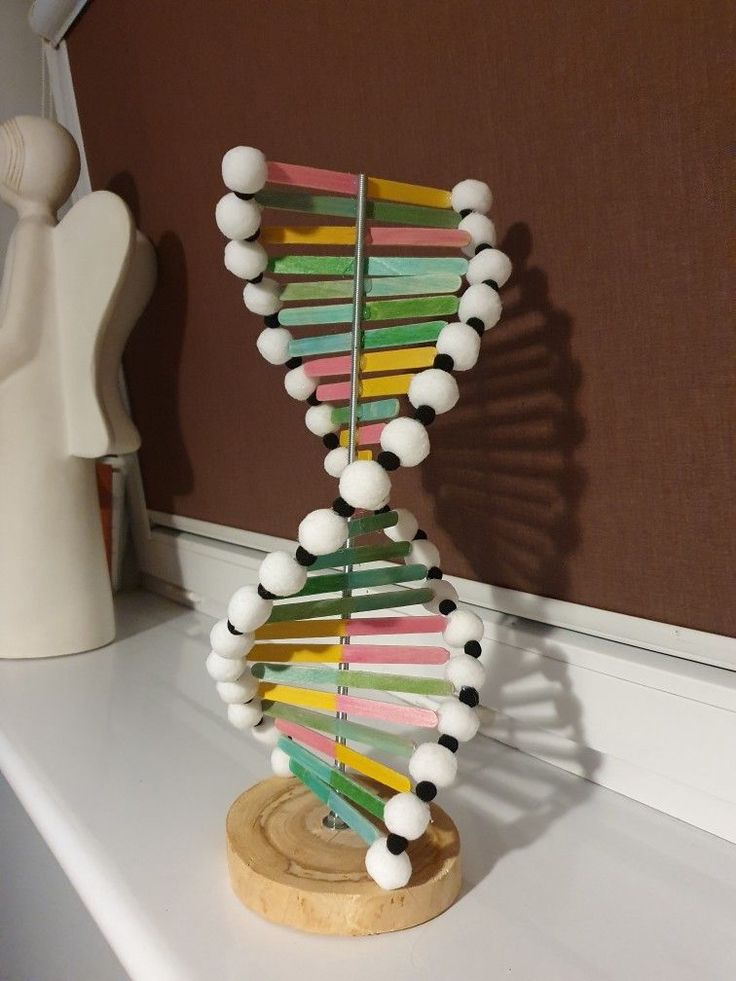 a sculpture made out of pops sticks on a white shelf next to a brown wall