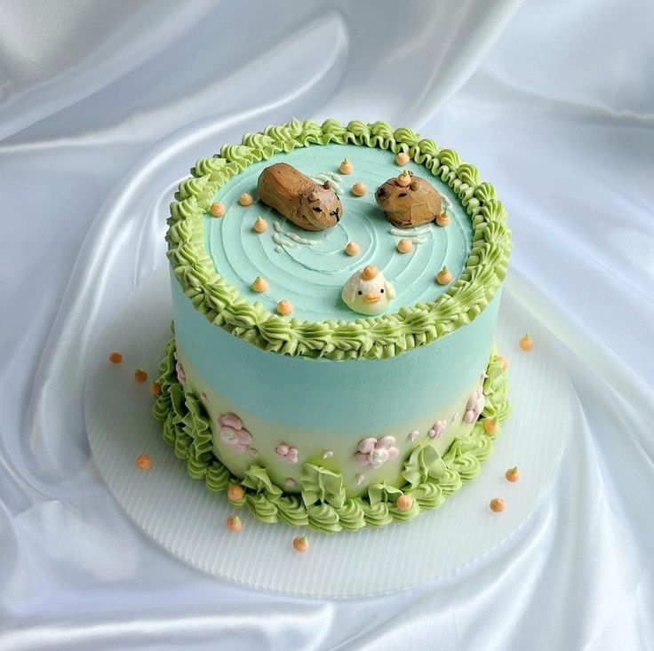 there is a cake decorated with animals and flowers on the top layer, sitting on a white table cloth