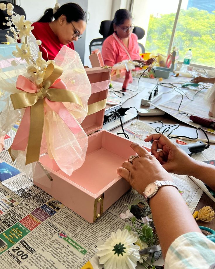 two women sitting at a table working on some crafting projects with paper and scissors