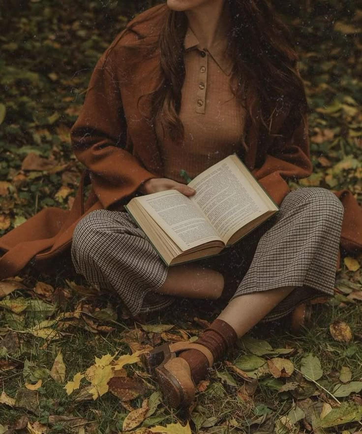 a woman sitting on the ground holding an open book