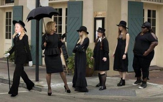 four women dressed in black are standing on the street