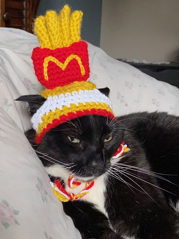 a black and white cat wearing a mcdonald's hat on top of a bed