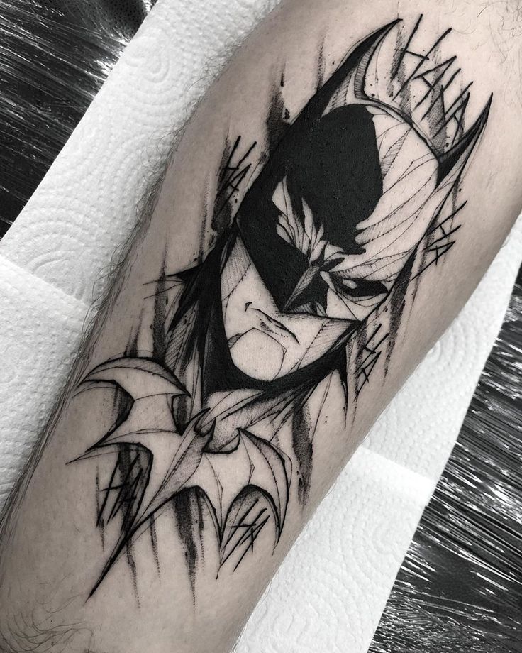 a batman tattoo on the arm with black and white lines around his head, in front of