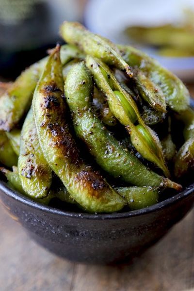 a bowl filled with green beans on top of a wooden table