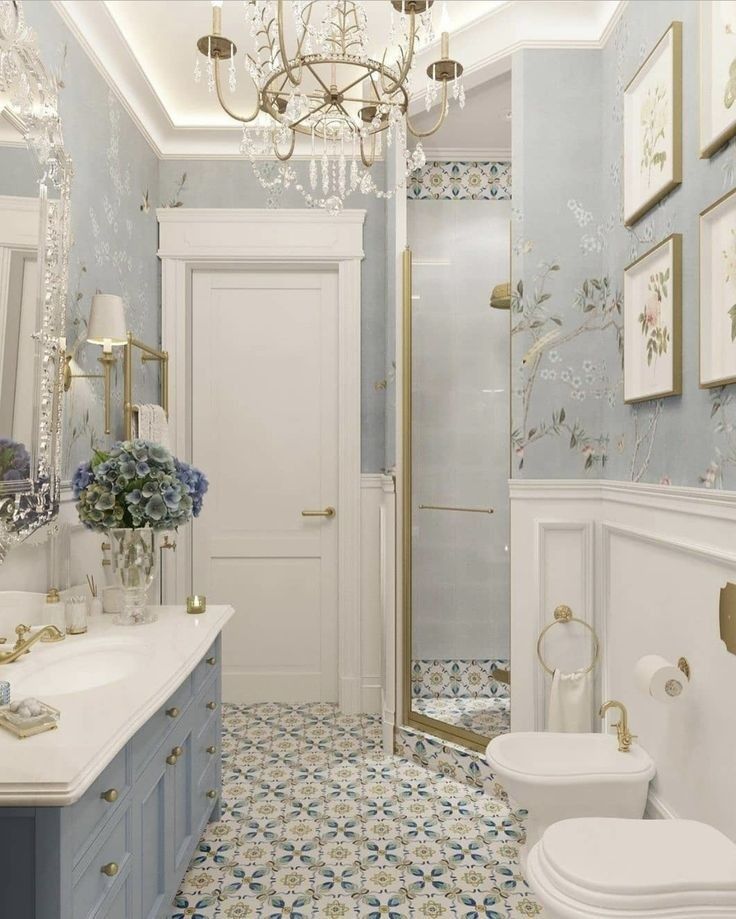 a white toilet sitting next to a bathroom sink under a chandelier in a bathroom