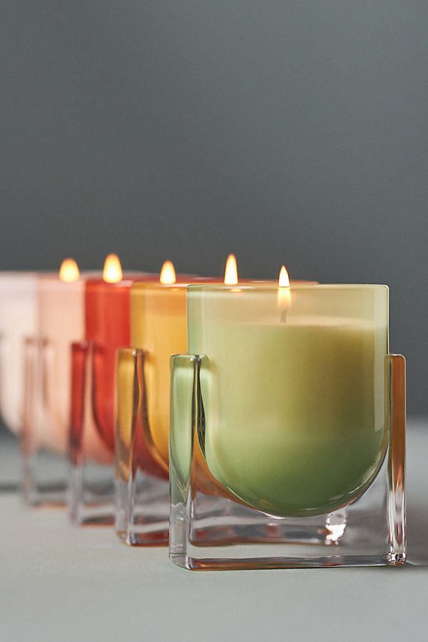 there are many different colored candles in the row on the table next to each other