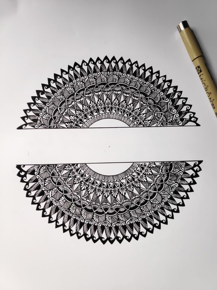 a pen is laying on top of a paper with an intricate design in the middle