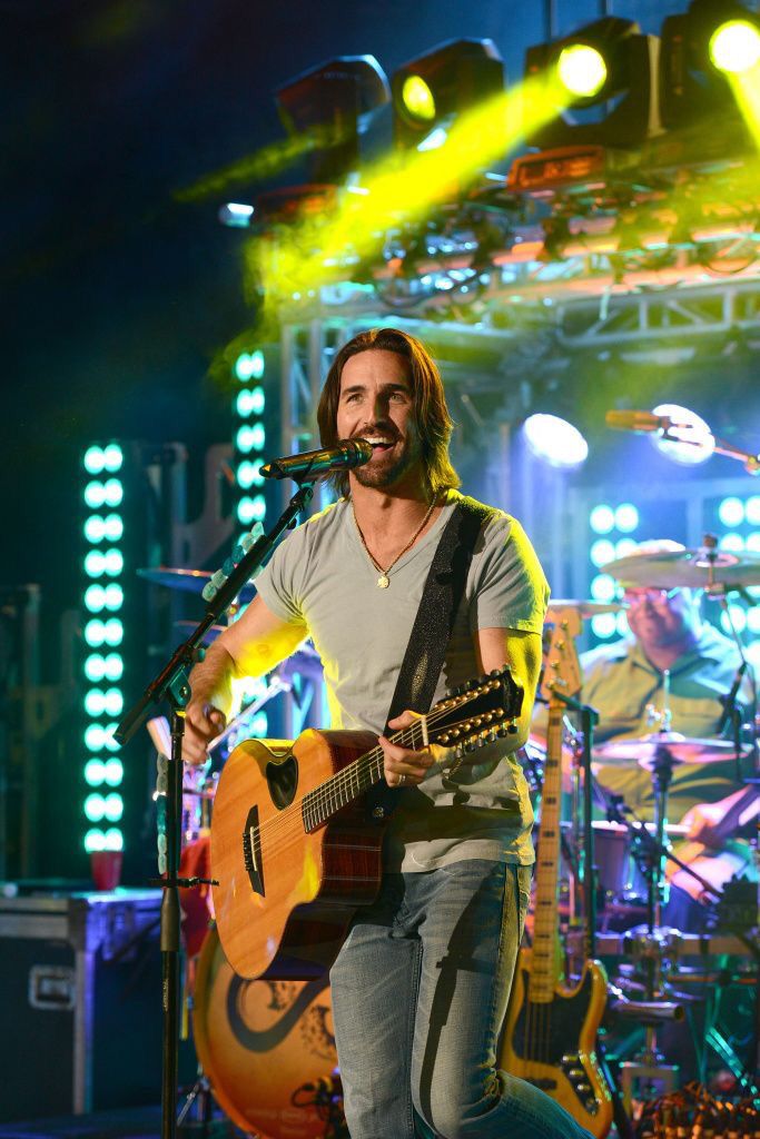 a man standing on top of a stage holding a guitar