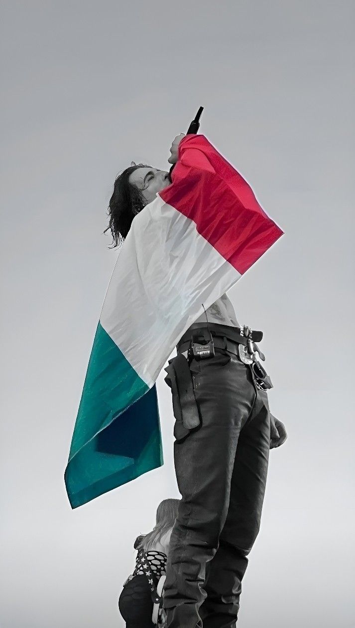 a man holding a flag while standing on top of a motorcycle