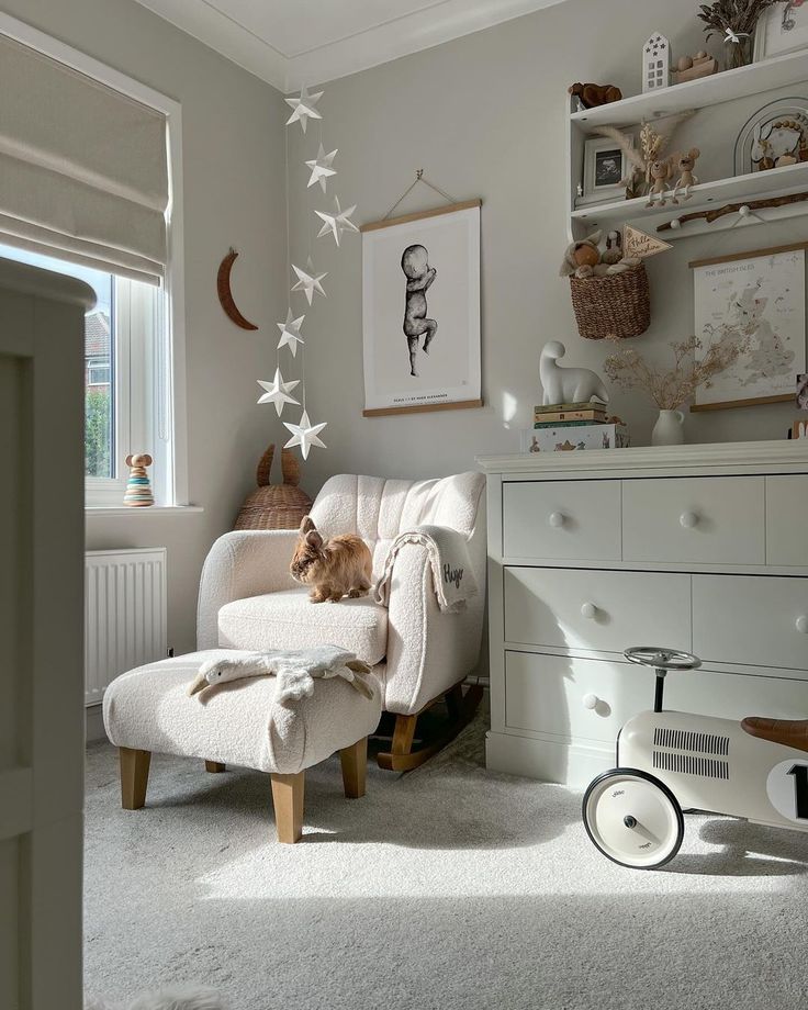 a living room with white furniture and stars on the wall above the chair is a cat