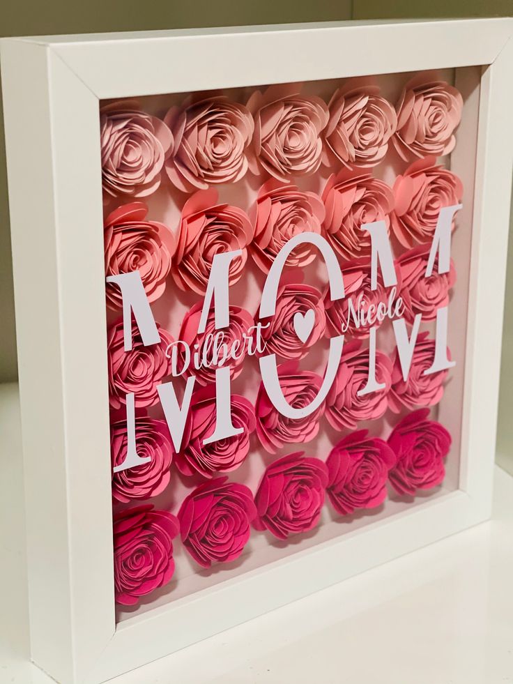 a white frame with pink and red paper flowers in it that says mom on the front