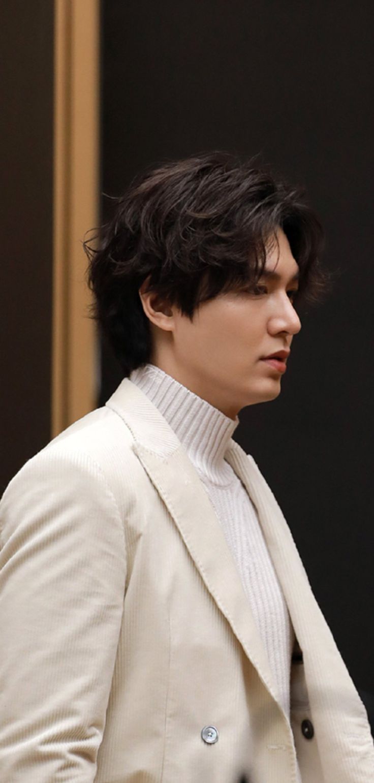 a young man in a white suit and turtle neck sweater looking off to the side