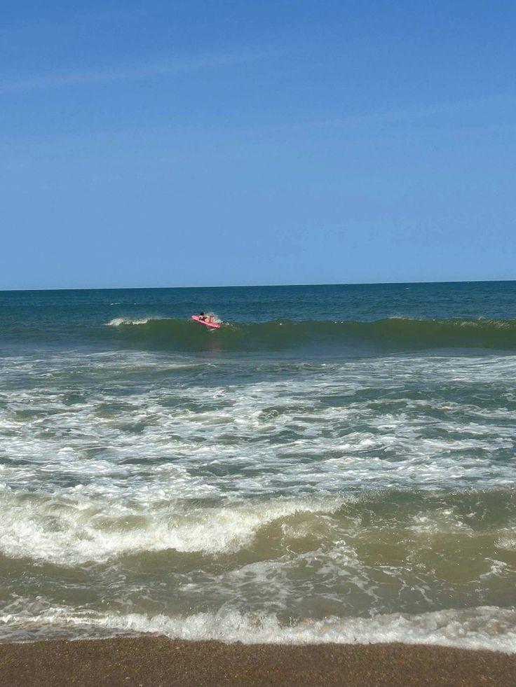 a person riding a surfboard on top of a wave in the ocean near shore