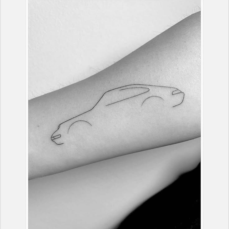 a black and white photo of a car tattoo on the left arm, with an outline of a car