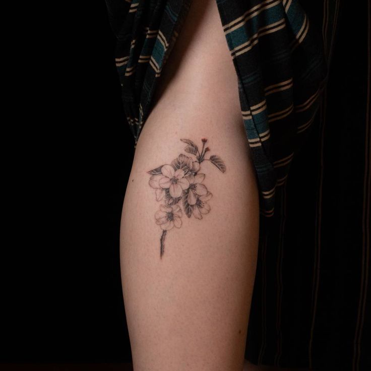 a woman's thigh with a flower tattoo on her left leg and the bottom half of her thighs