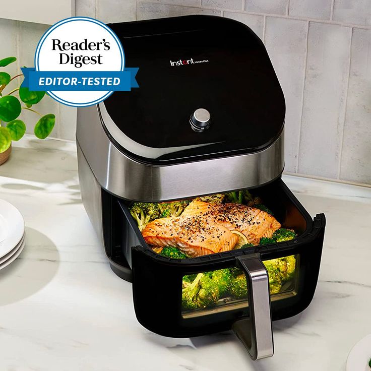 a black and silver air fryer sitting on top of a counter next to plates