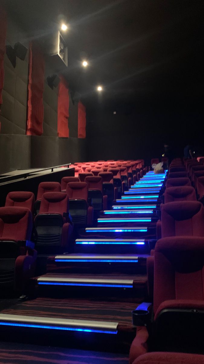 an empty theater with red seats and blue lights