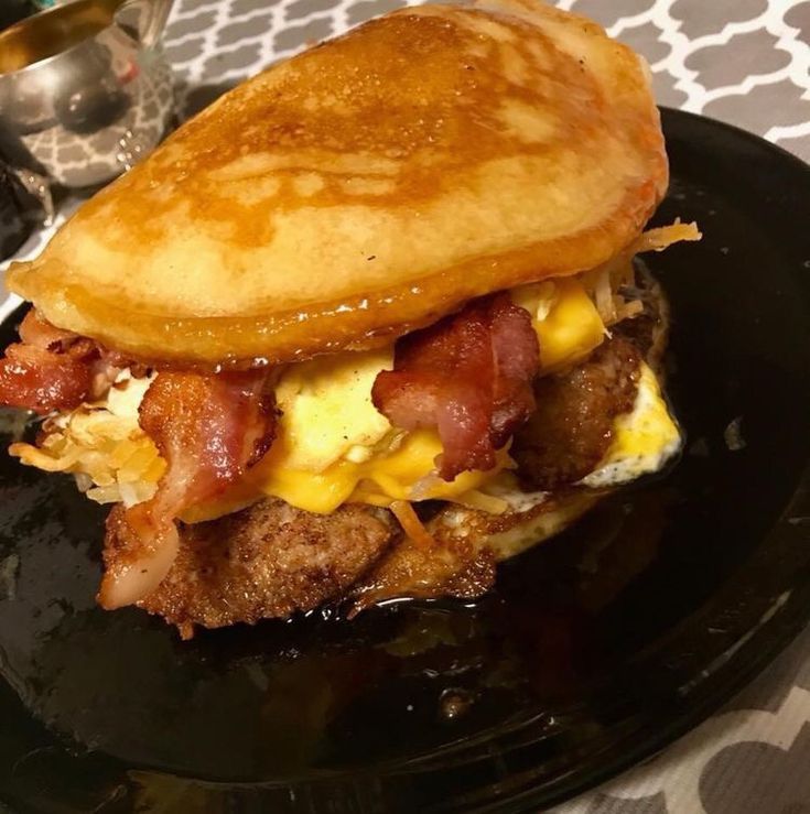 a black plate topped with a breakfast sandwich