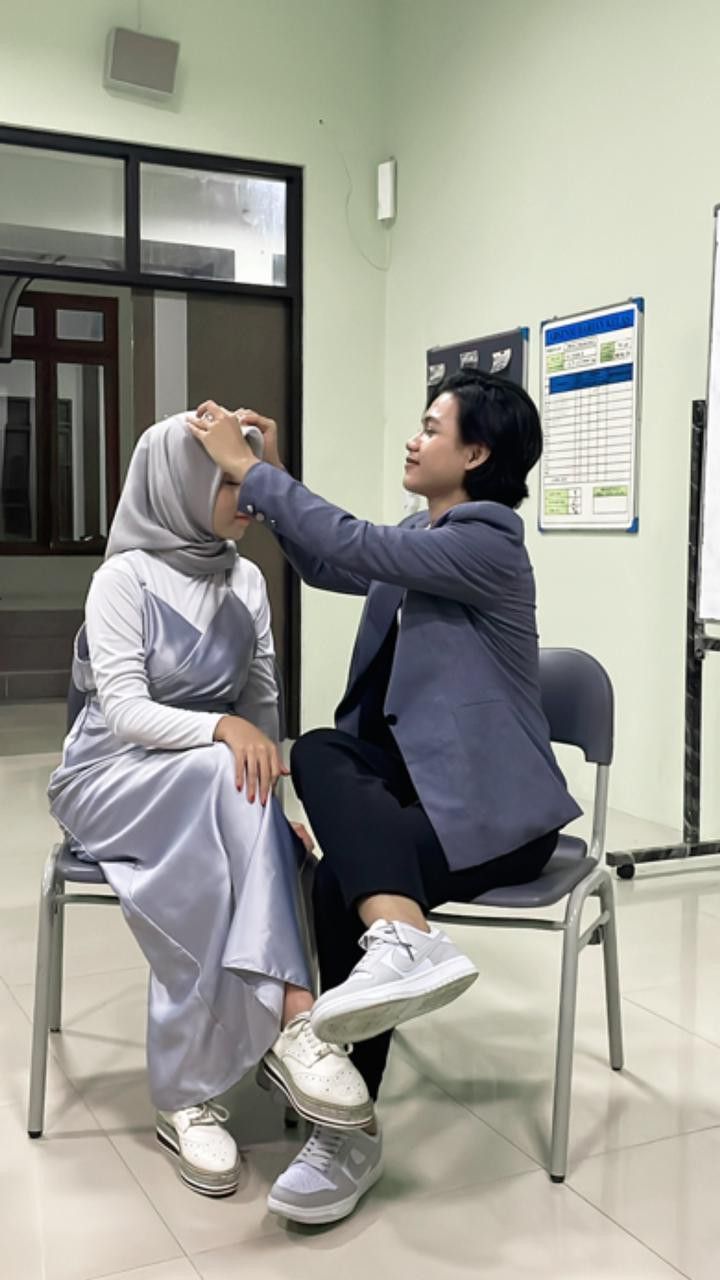 a woman sitting in a chair getting her hair combed by another woman who is wearing a hijab