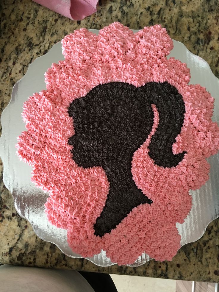 a pink and black cake with a woman's silhouette on it sitting on top of a counter