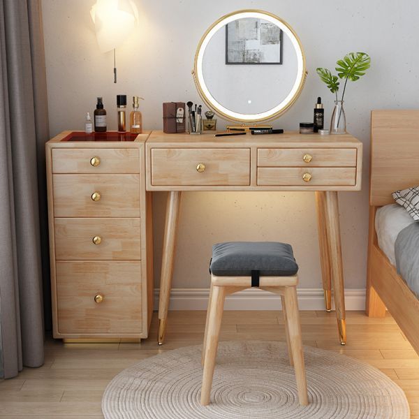 a wooden desk with a mirror and stool in front of it on a rug next to a bed