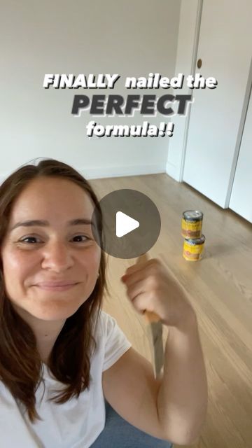 a woman sitting on the floor with a knife in her hand and paint cans behind her