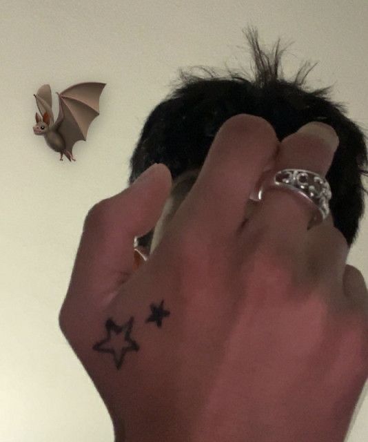 a man's hand with tattoos on it next to a bat and star tattoo