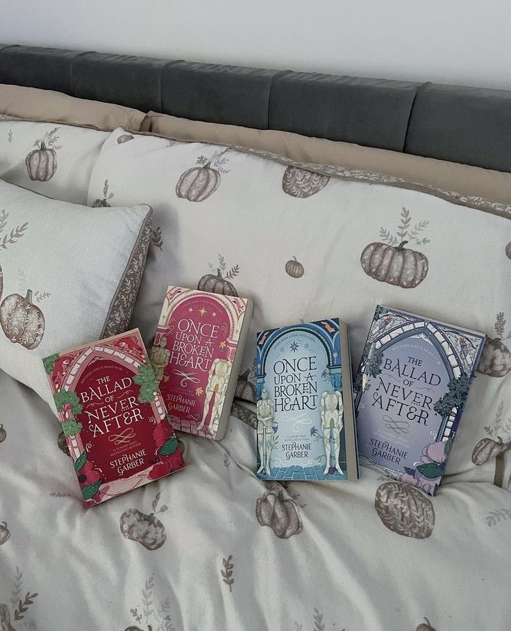 three books are laying on the bed with pillows and covers in front of each other