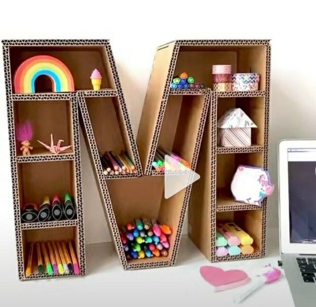 a laptop computer sitting on top of a desk next to a wooden letter shaped like a bookcase