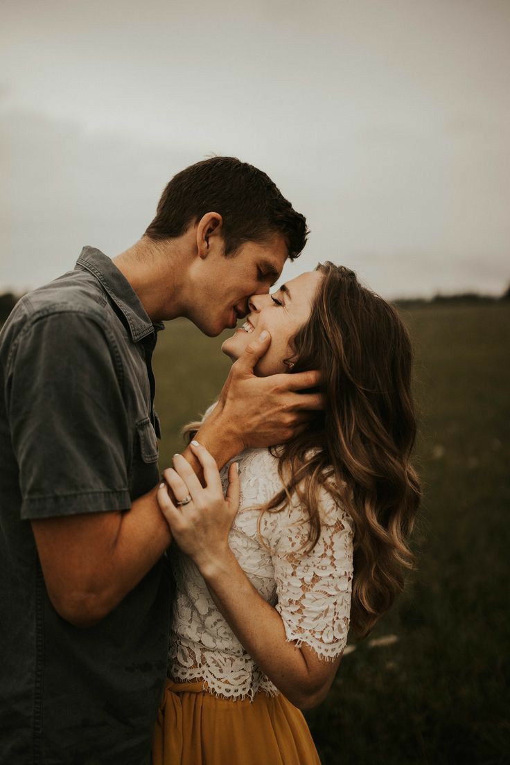 a man and woman kissing in an open field