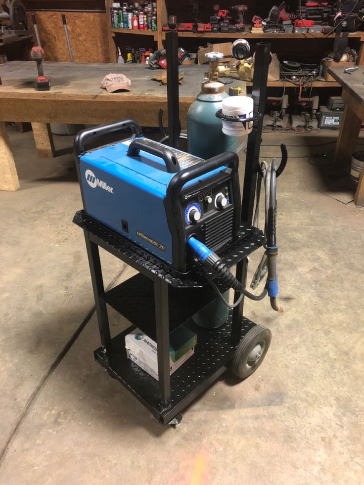 a blue and black air compressor sitting on top of a cart in a garage next to other tools