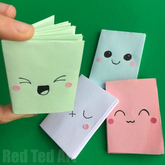 someone is holding up some folded paper with faces on it and eyes drawn on them