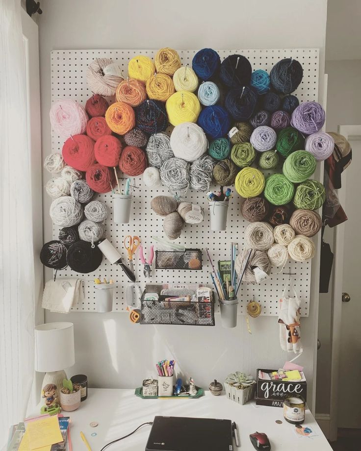 a white desk topped with a laptop computer and lots of yarn on top of it